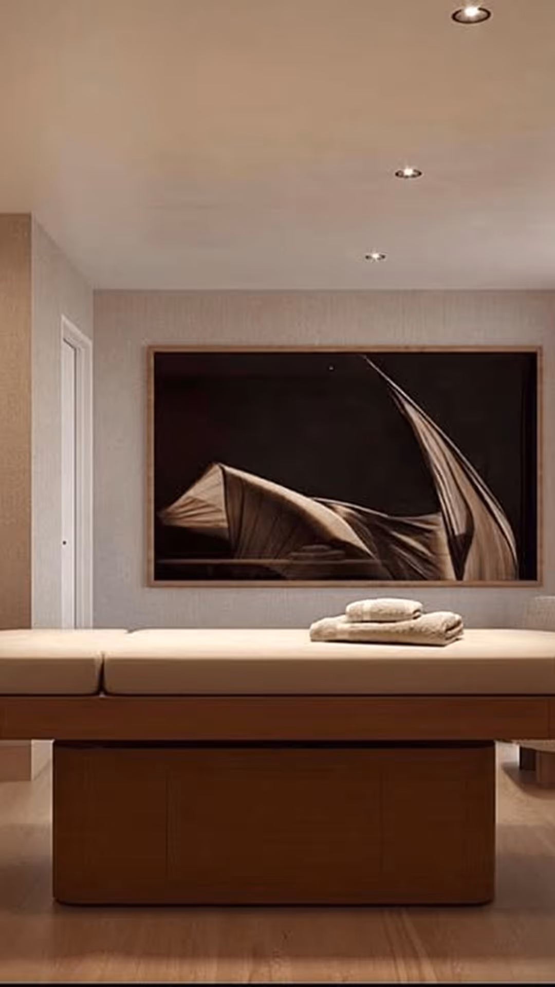 Massage table with folded towels in a calm room with abstract wall art and recessed lights, Mr. C Miami – Coconut Grove, luxury hotel.