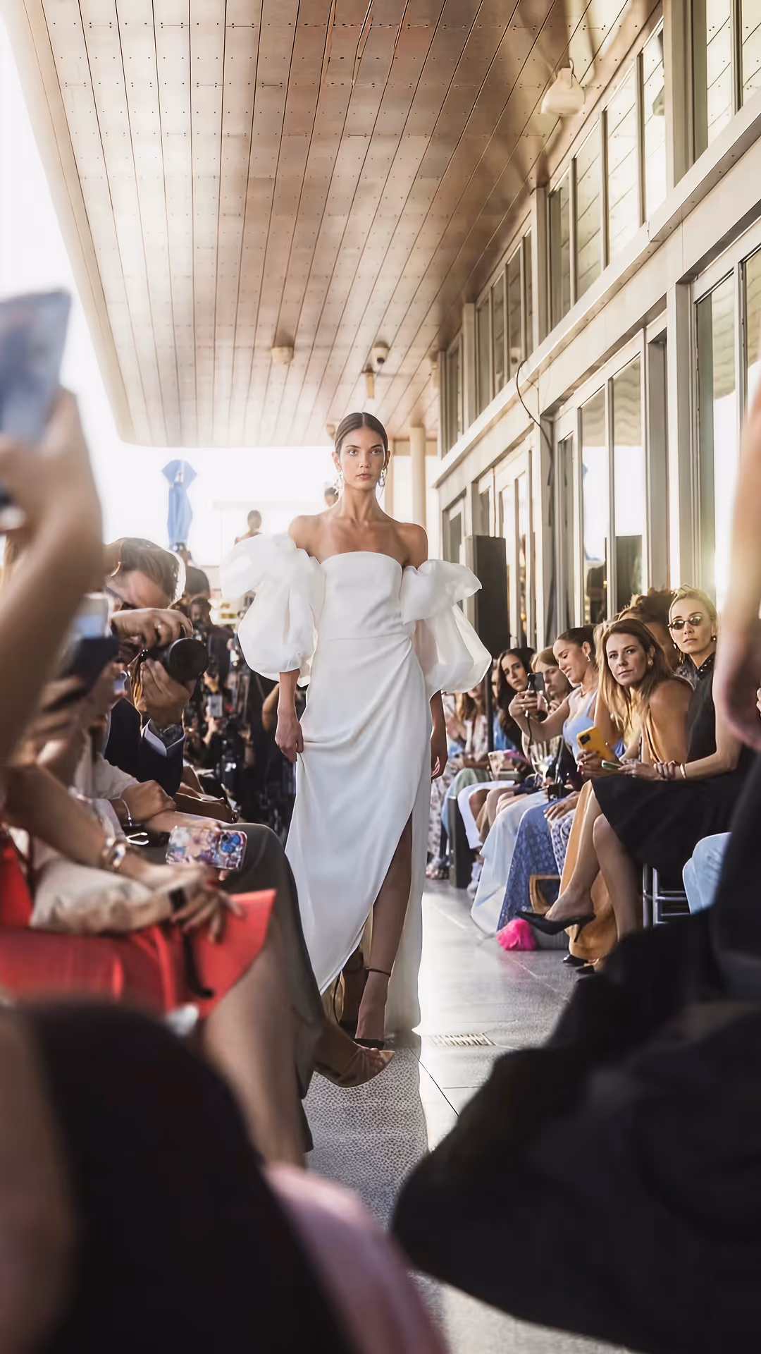 Model walking runway in a white off-shoulder dress with puff sleeves at a fashion show, Mr. C Miami – Coconut Grove, luxury hotel.
