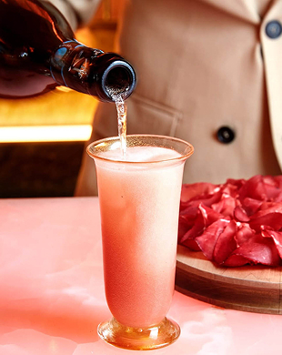 A bottle pouring a beverage into a tall glass with pink foam on a pink table
, Mr. C Miami – Coconut Grove, luxury hotel.