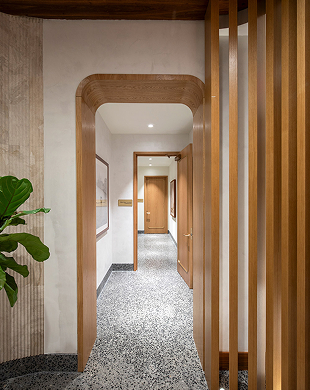 Corridoio moderno con arco in legno, pavimento in terrazzo, doghe verticali in legno e porte in legno chiuse.