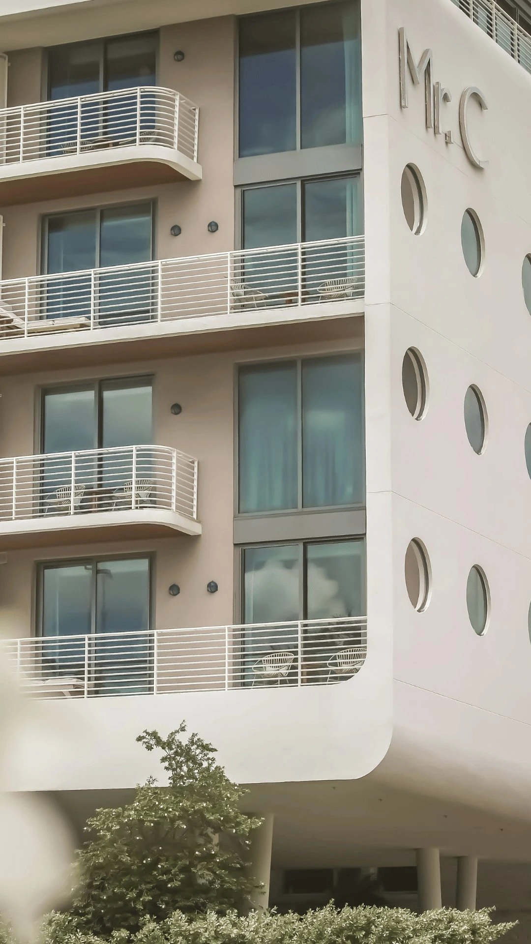 Fachada de edificio moderno con balcones y ventanas redondas, con el letrero del Sr. C en la pared superior.