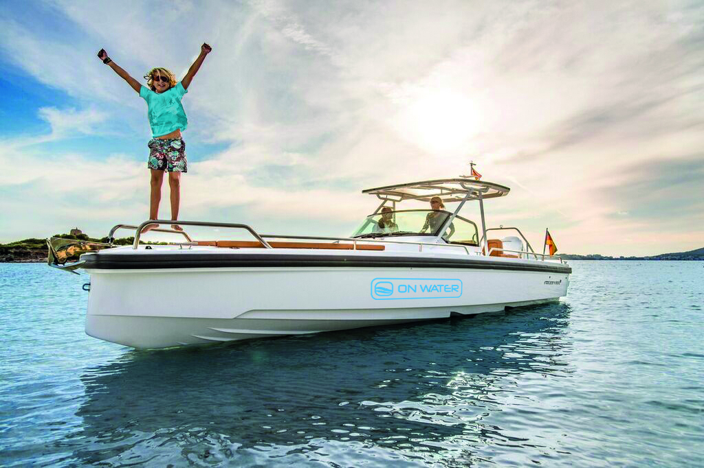 Weißes Axopar-Motorboot mit ON-WATER-Logo auf ruhiger See, ein Kind steht mit ausgebreiteten Armen auf dem Bug