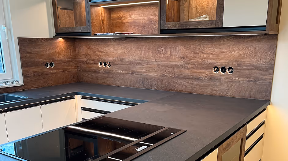 Moderne Küche mit dunkler Arbeitsplatte, Holzwandverkleidung und Einbauherd.