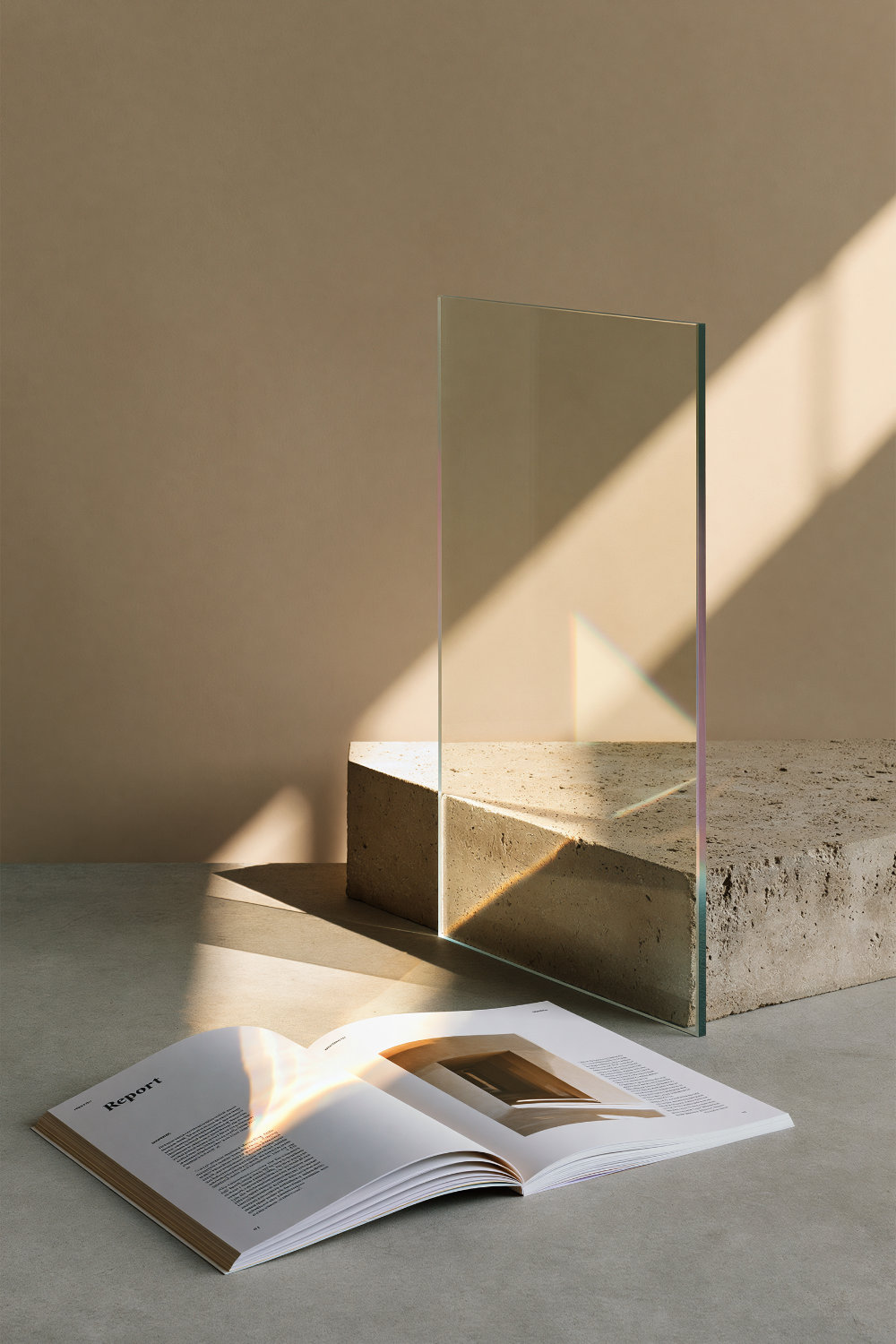 Offenes Magazin mit dem Titel Bericht liegt auf grauem Boden neben einem Glasstück auf einem Steinblock.