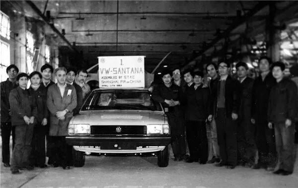 Workers next to the first VW Santana assembled in Shanghai in the 1980s
