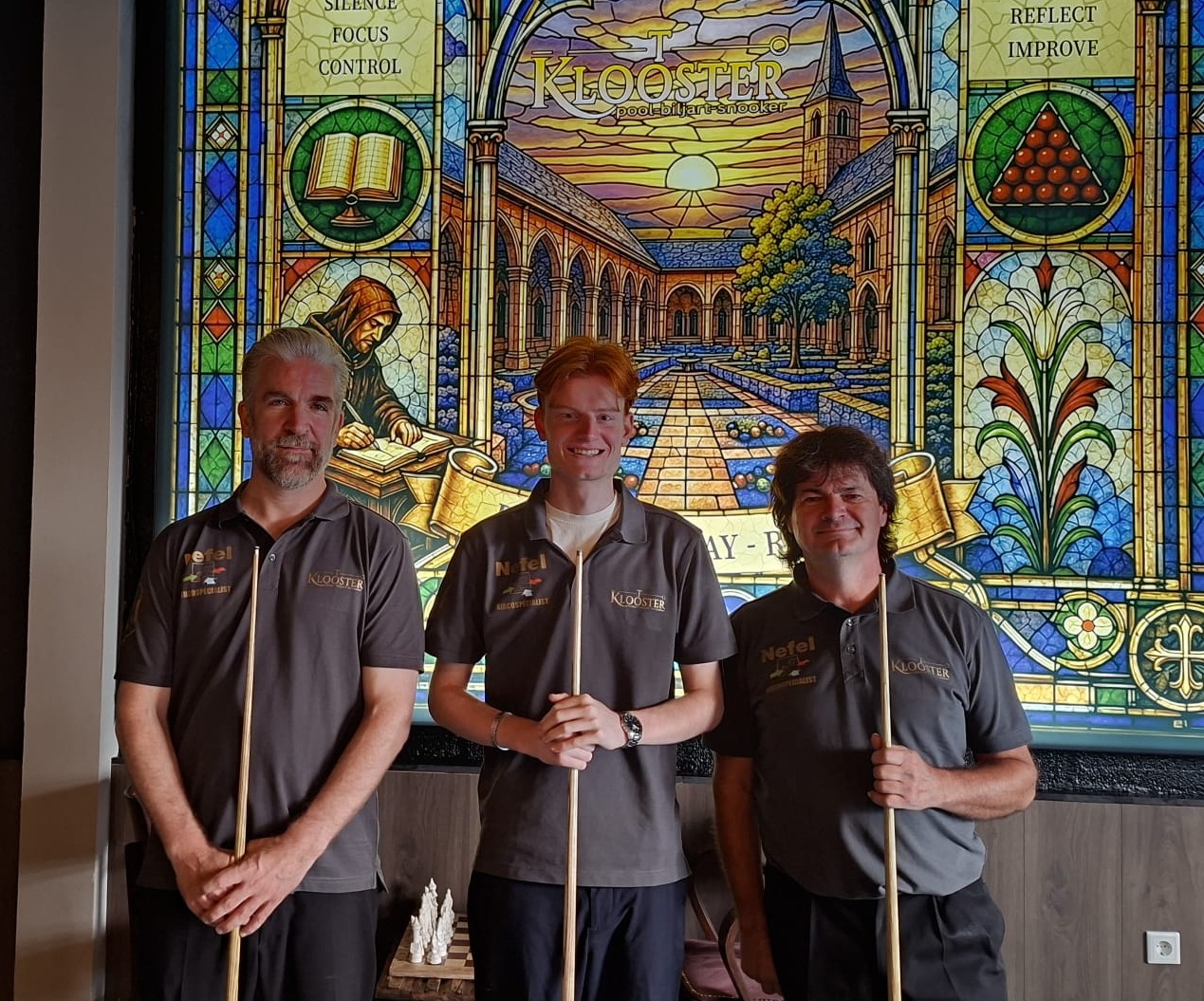 Drie spelers van ’t Klooster met hun keu voor het glas-in-loodpaneel