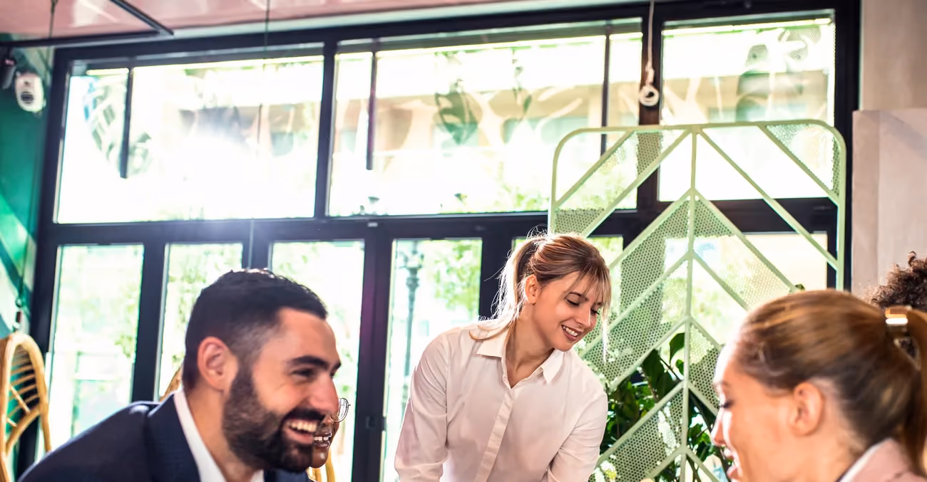 Restaurant staff serving guests at a table in a busy dining room.