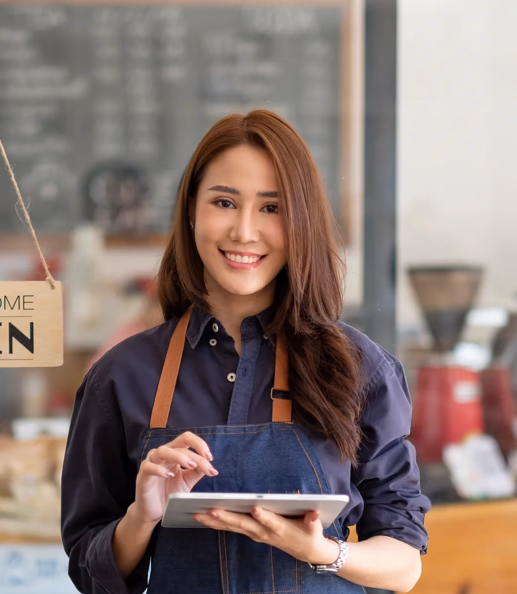 Café staff member checking a tablet by the front window.