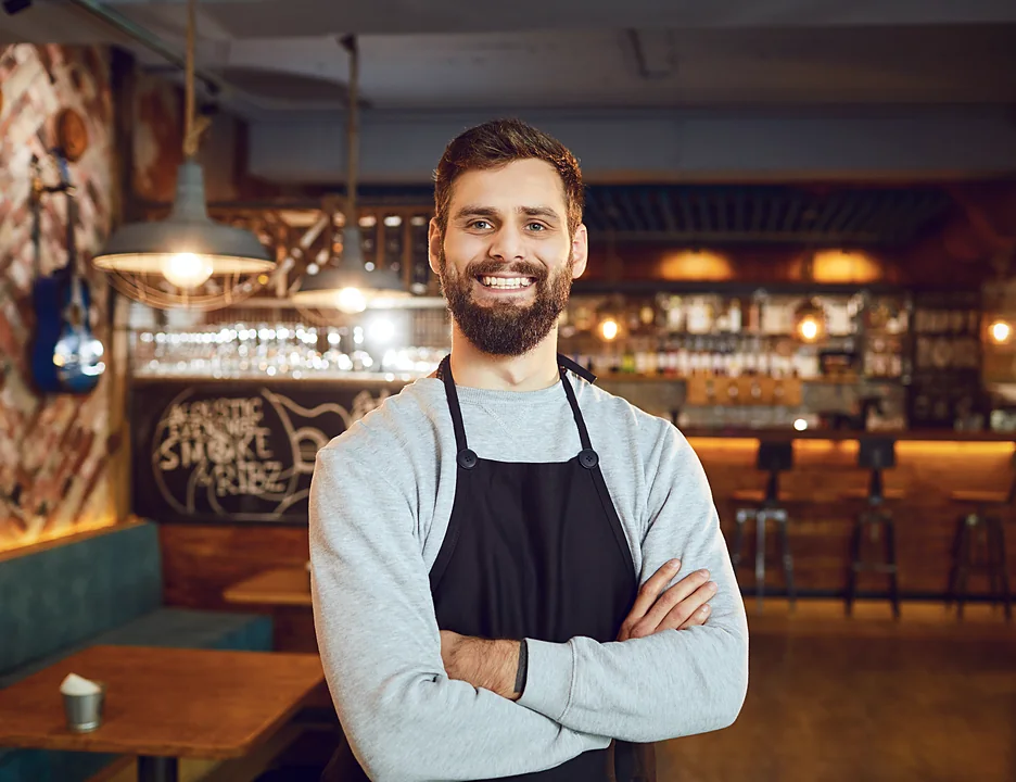 Smiling bar worker in an apron whose tips land on a Ferry Pay Card at shift end.