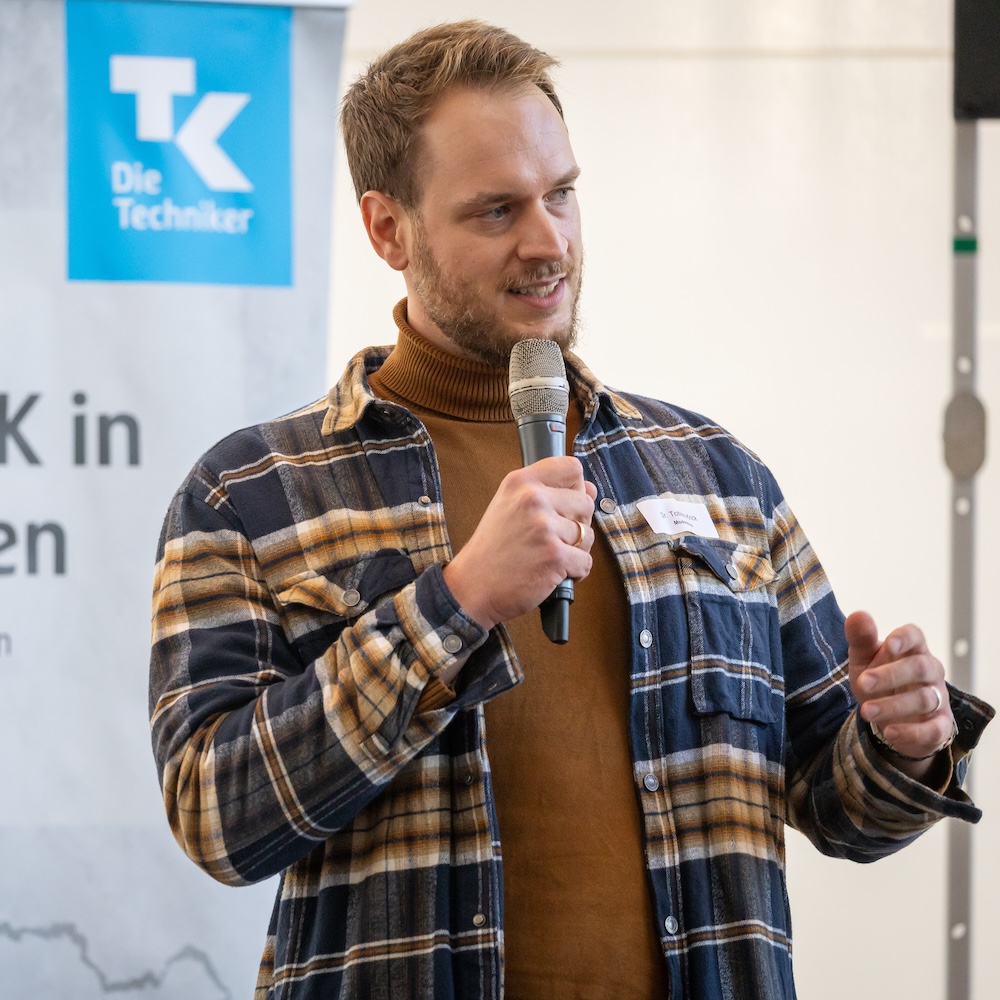 Dr. Tobias Krick als Keynote Speaker mit Mikrofon auf einer Veranstaltung im Gesundheitswesen