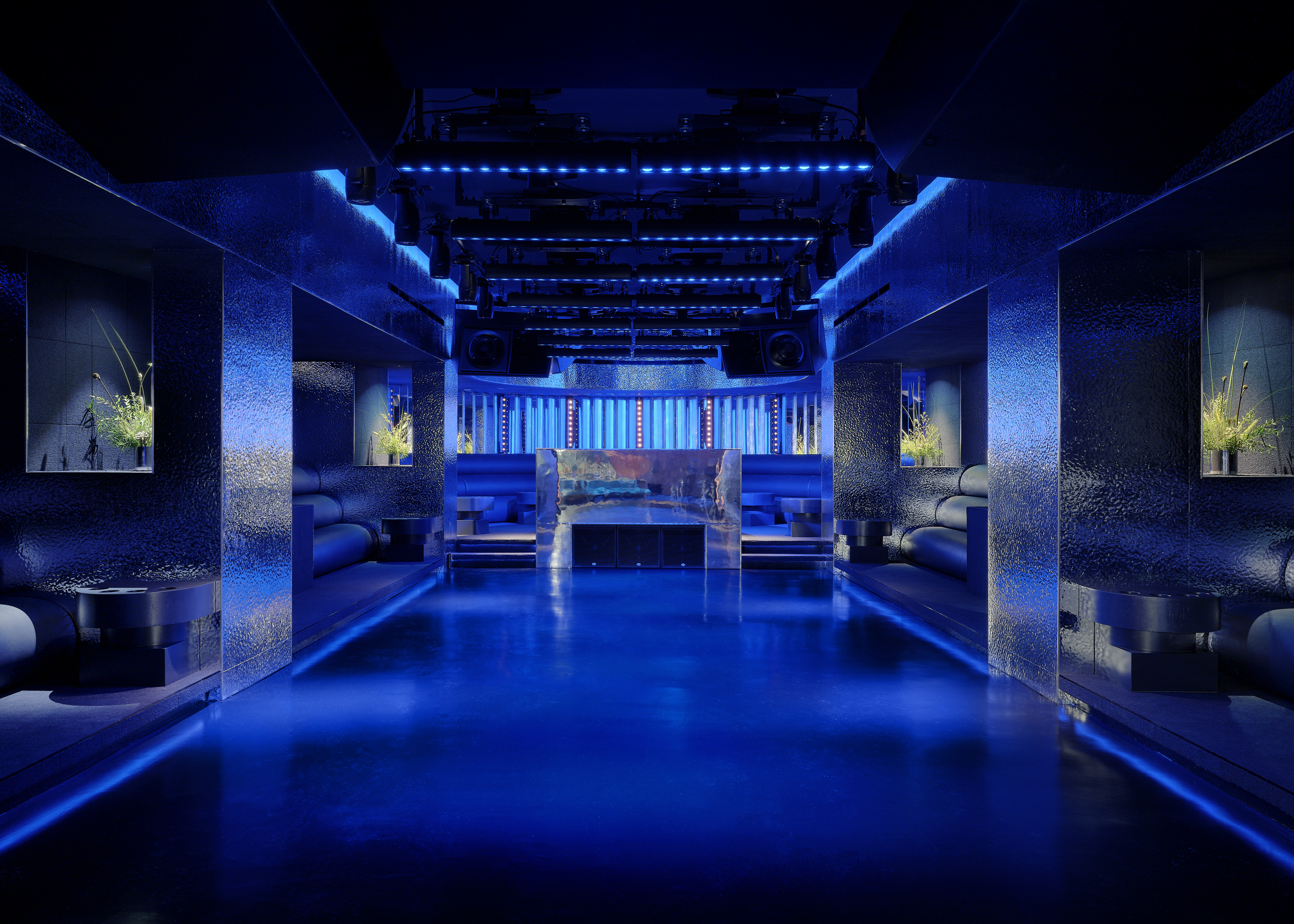 Blue-lit main room at Unveiled with a central booth and built-in seating.