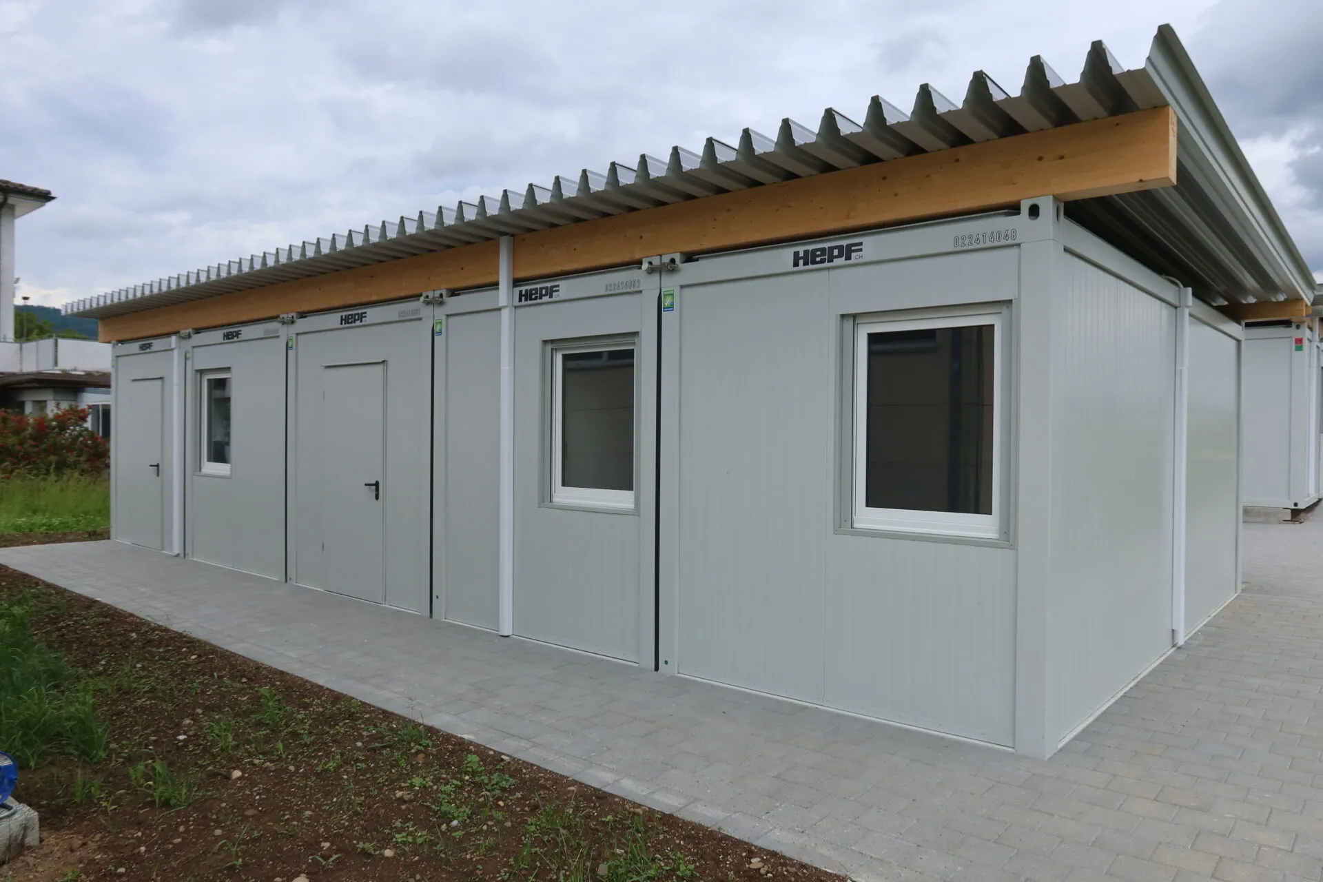 Fully completed modular refugee housing facility in Hüttikon, featuring connected containers, a pitched roof, and Ac's.
