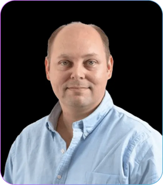 Portrait of a man with short hair wearing a light blue button-up shirt against a black background.