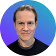 Portrait of a smiling man with light skin and slicked-back hair against a blue and purple gradient background.
