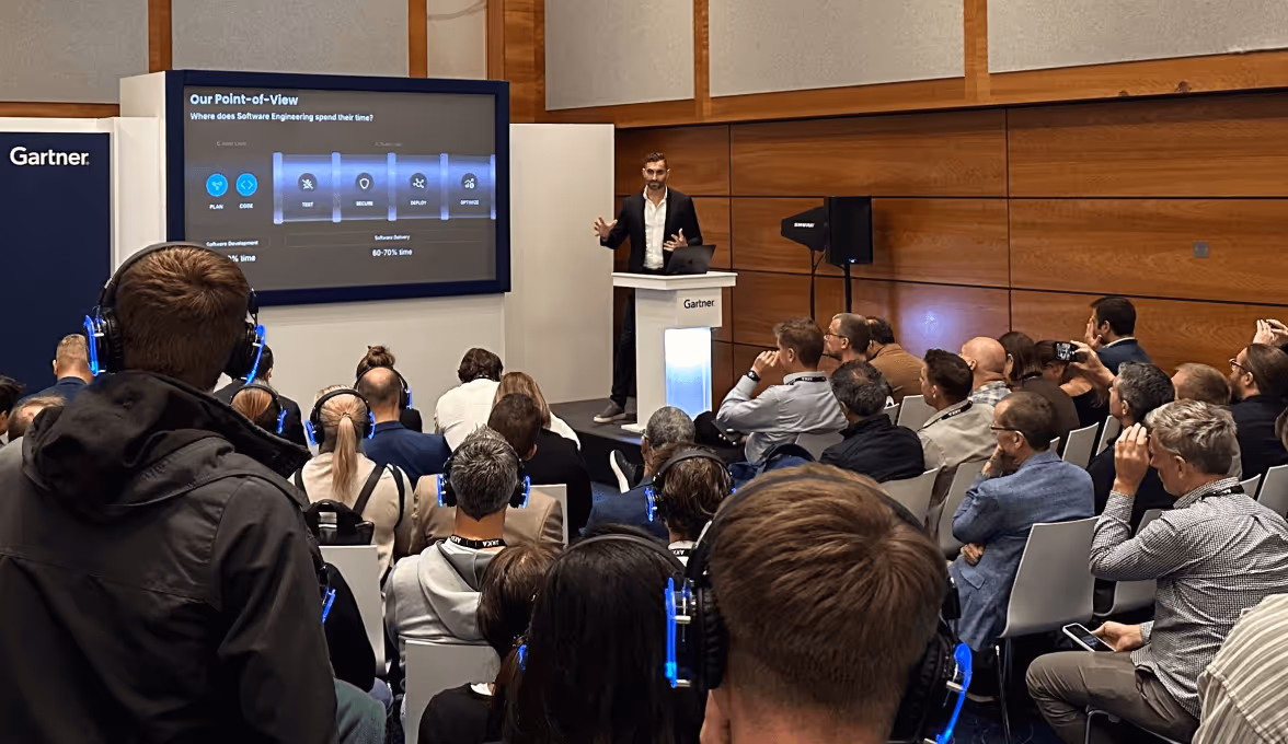Man in suit giving a presentation on software engineering to an audience wearing blue-lit headphones in a conference room.