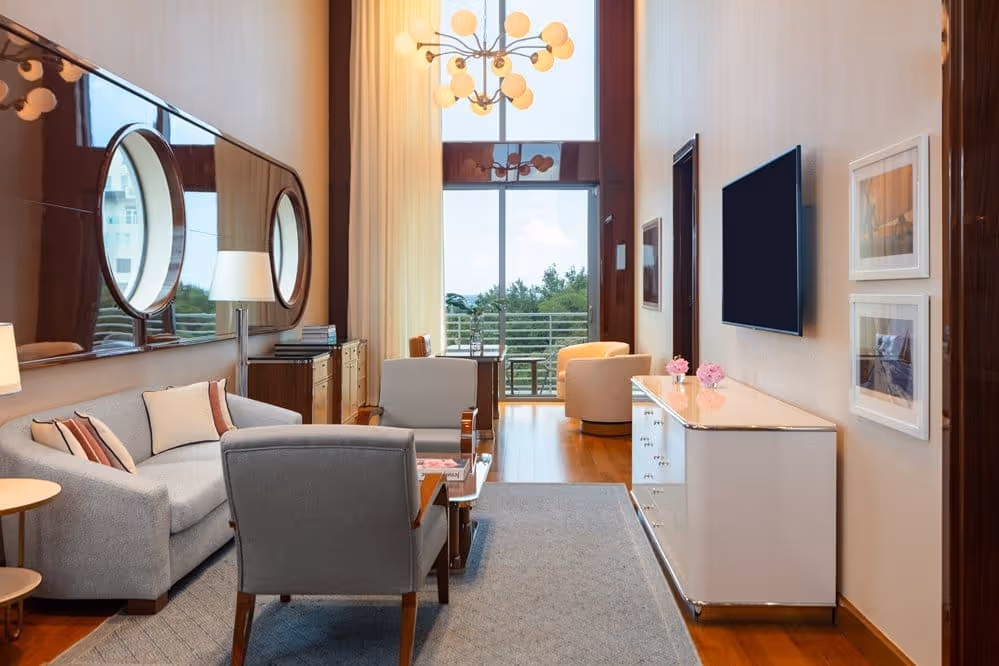 Sala de estar com sofás cinzas e vista para a varanda no Mr. C Miami – Coconut Grove, um hotel de luxo em Miami.