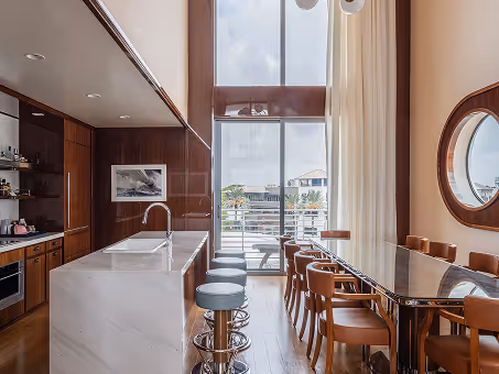 Área de refeições com ilha de cozinha, banquetas e uma mesa comprida. Mr. C Miami – Coconut Grove, um hotel de luxo.