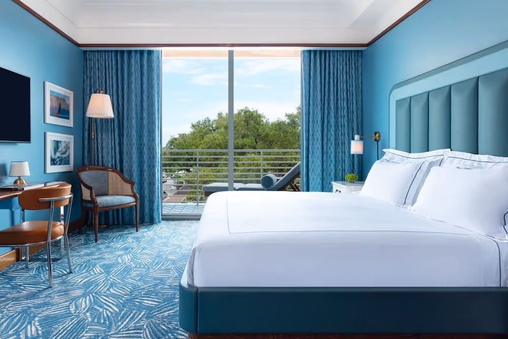 Quarto com cama king-size, bancada de trabalho e lounge na varanda no Mr. C Miami – Coconut Grove, um hotel de luxo em Miami.