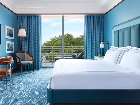 Quarto King convidativo com carpete de padrão azul, cabeceira e varanda privativa no Mr. C Miami – Coconut Grove.
