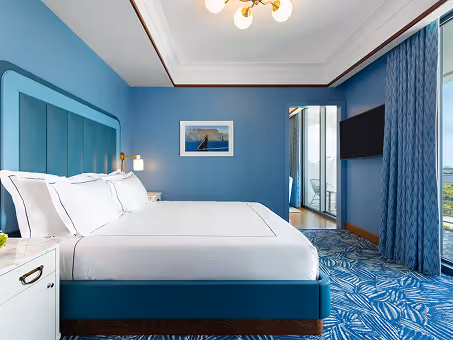 Quarto de hotel com papel de parede azul texturizado e uma cama grande no Mr. C Miami – Coconut Grove, um hotel de luxo em Miami.