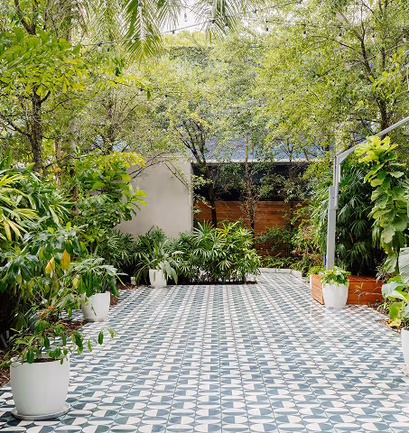 Garden seating area at Il Giardino featuring lush foliage and decorative floor tiles. Mr. C Miami – Coconut Grove.