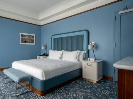 Vista de uma cama king size no quarto de hotel com paredes azuis. Mr. C Miami – Coconut Grove, um hotel de luxo em Miami.