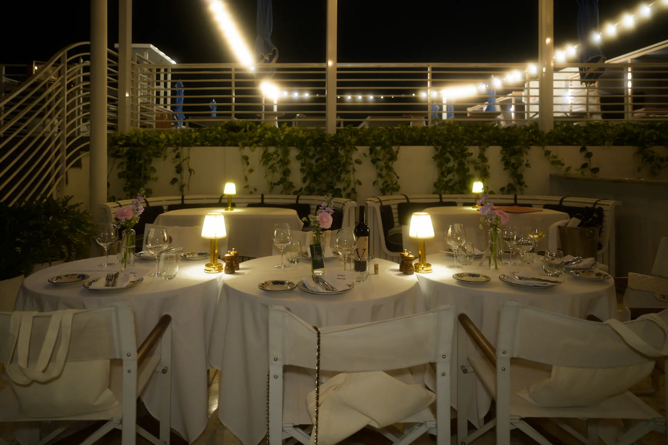 Elegant dining tables on the Bellini patio at night, illuminated by soft string lights. Mr. C Miami – Coconut Grove, hotel.