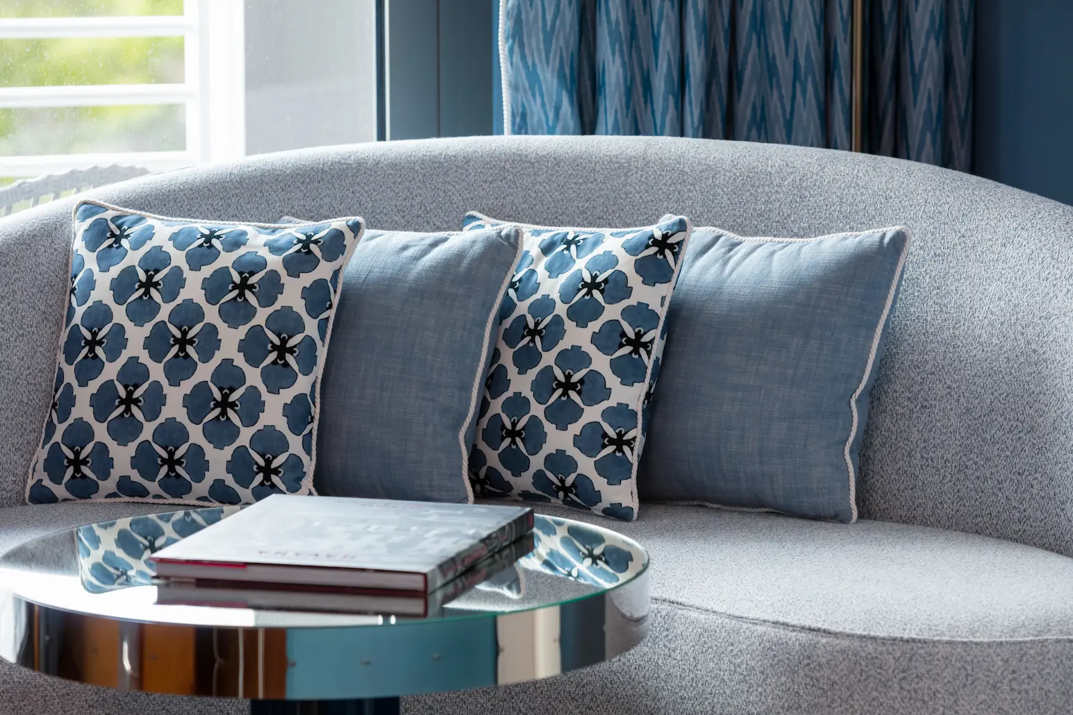 Vista aproximada de um sofá curvo com quatro almofadas estampadas em um quarto no Mr. C Miami – Coconut Grove.