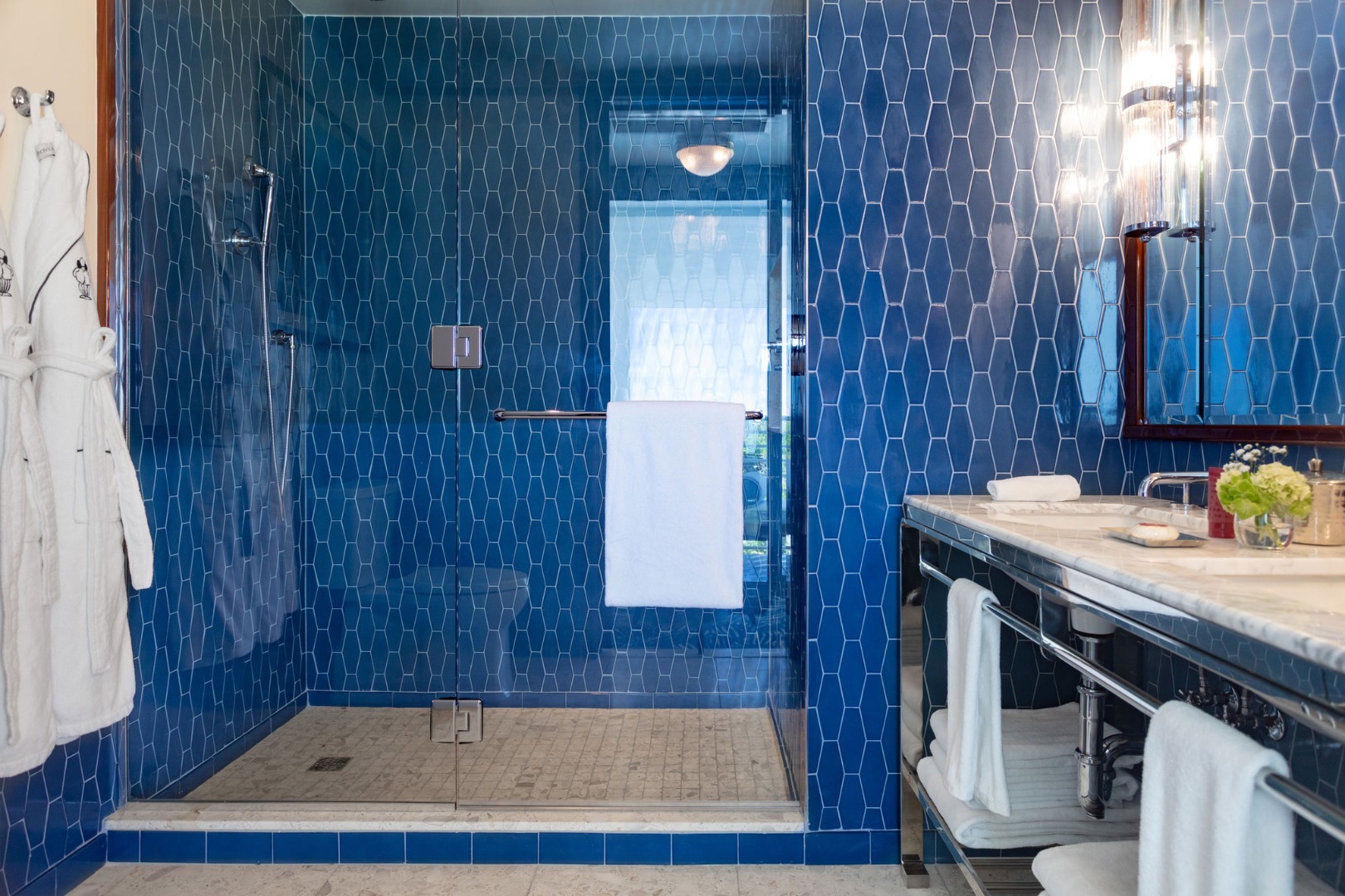 O chuveiro com azulejos azuis e um canto da bancada no banheiro do Mr. C Miami – Coconut Grove, um hotel de luxo.