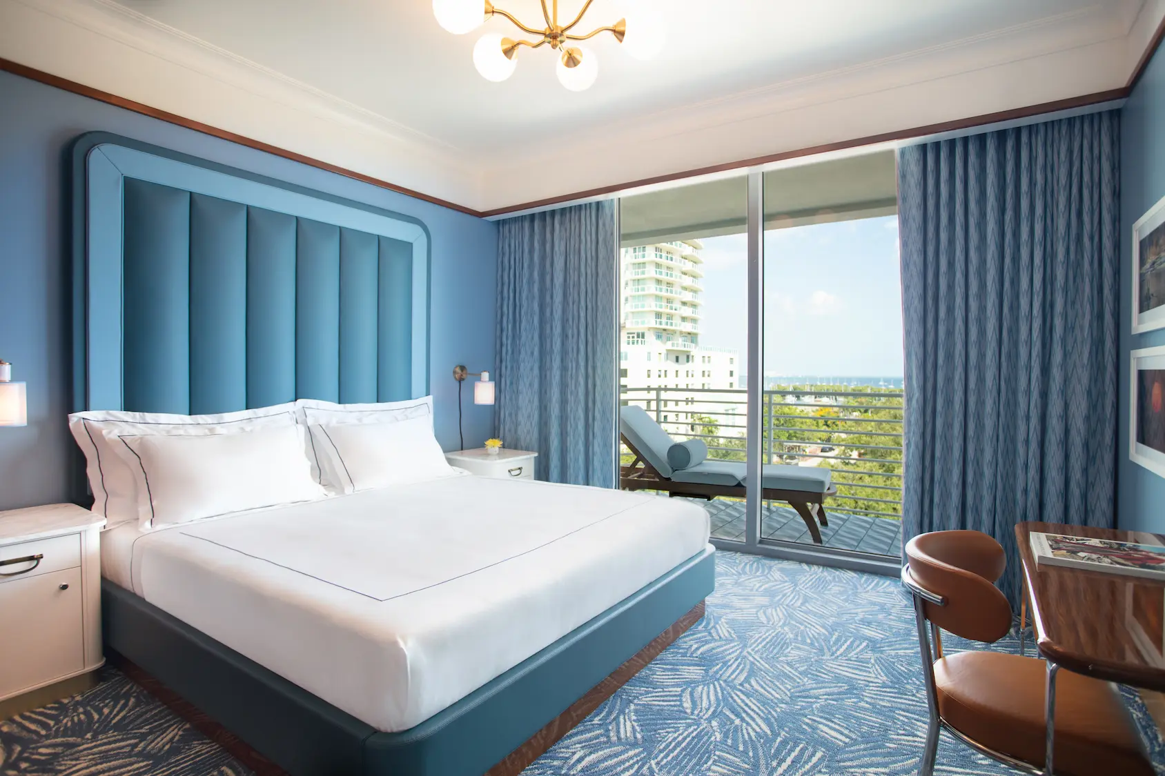 Quarto de luxo no Mr. C Miami – Coconut Grove, um hotel de luxo em Miami, com cama king-size e varanda com espreguiçadeiras.