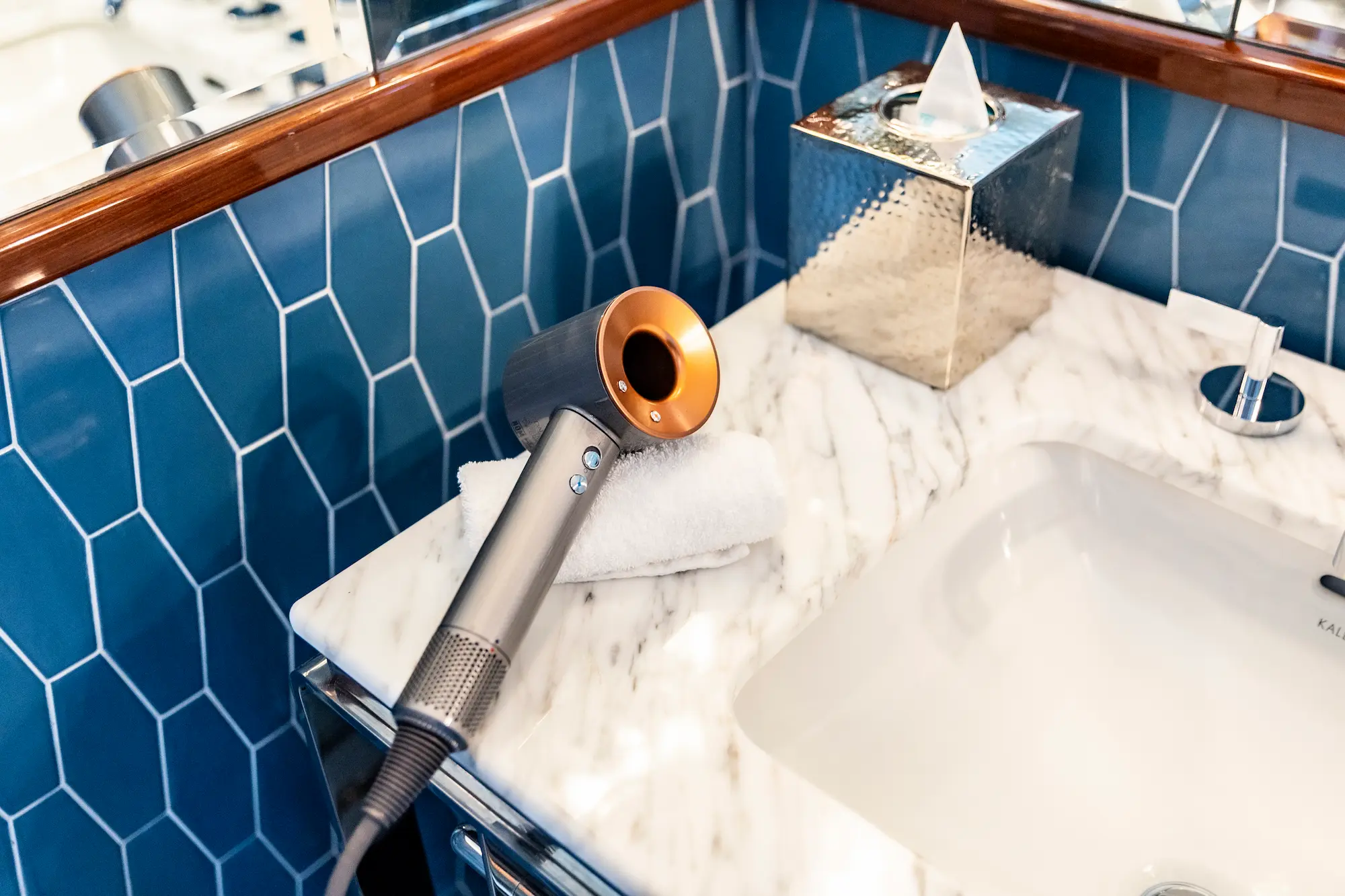 Secador de cabelo Dyson Supersonic sobre a bancada de mármore do banheiro no Mr. C Miami – Coconut Grove, um hotel de luxo.