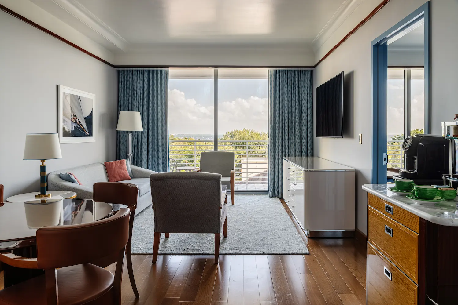 Vista da área de estar com sofá cinza, poltronas e mesa de jantar no Mr. C Miami – Coconut Grove, um hotel de luxo em Miami.