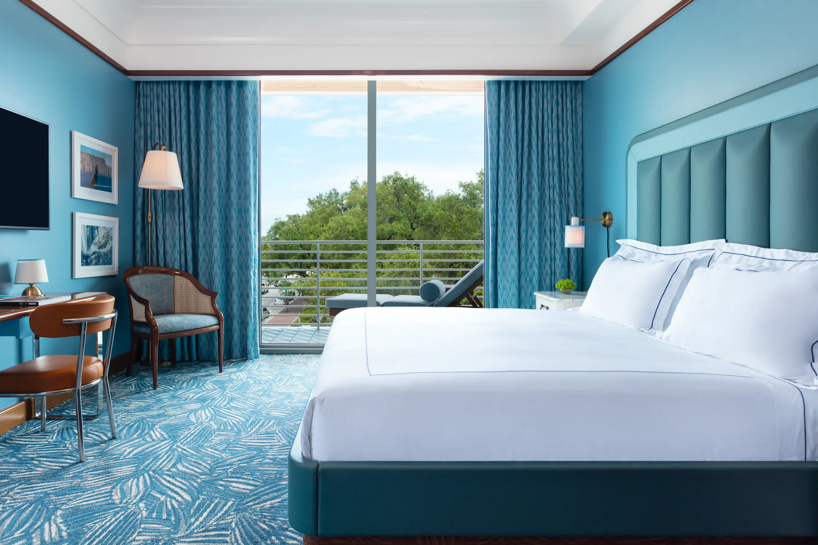 Quarto de hóspedes elegante com cama king-size, revestimento de madeira nobre, detalhes em azul e vista para a varanda no Mr. C Miami.