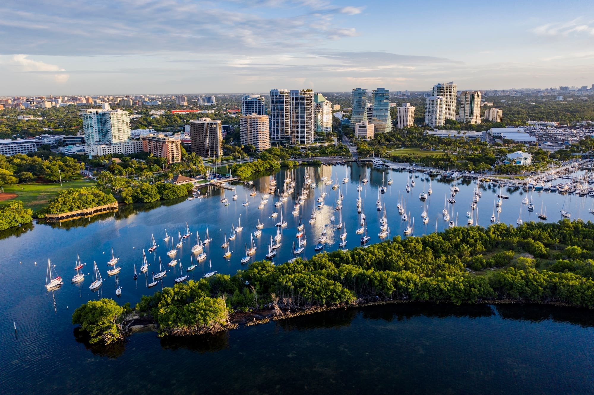 Vue aérienne d'une marina avec de nombreux voiliers amarrés près d'un paysage urbain composé de gratte-ciel et de verdure, Mr. C Miami – Coconut Grove, hôtel de luxe.