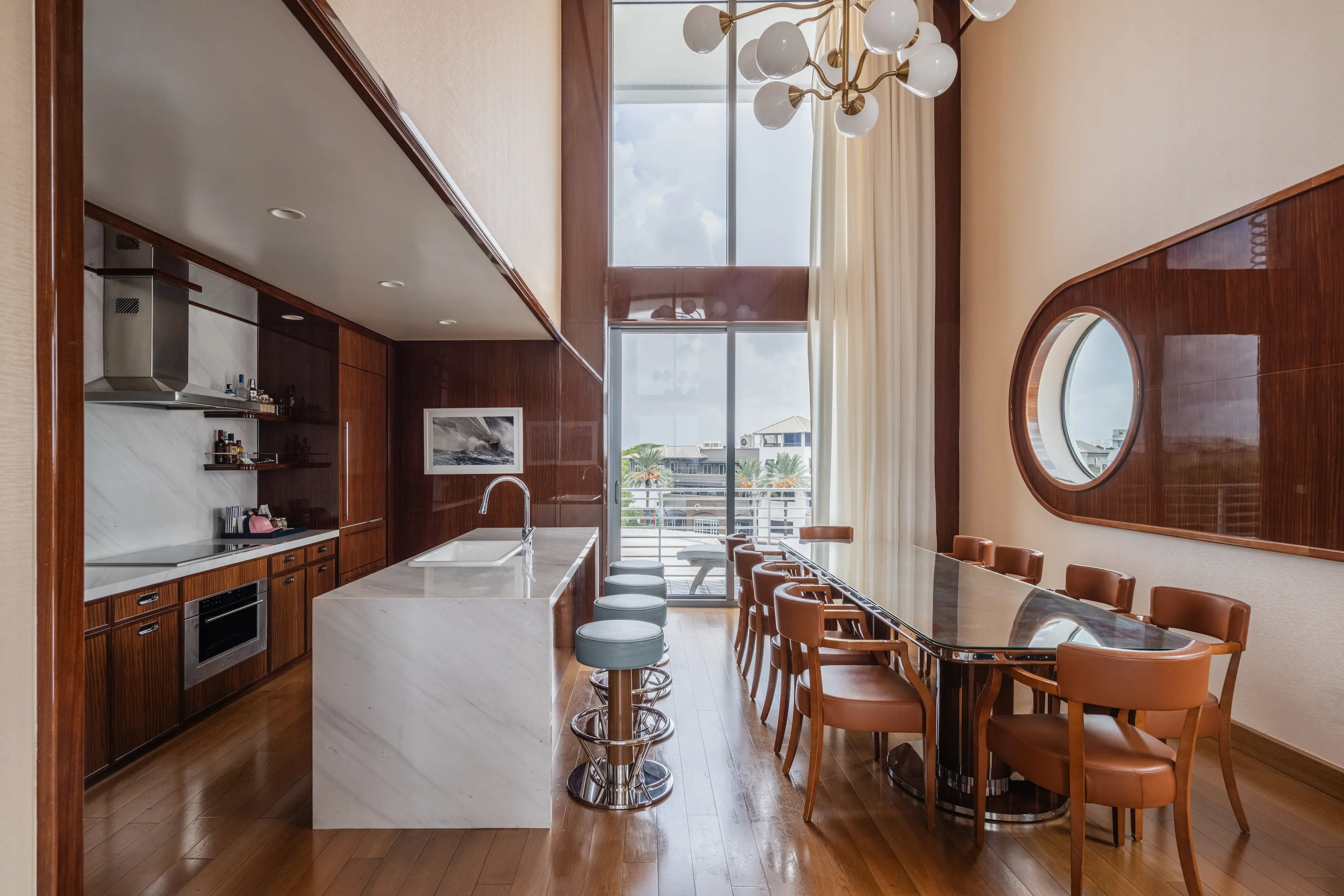 Espaço loft moderno de dois andares com bancada de cozinha, mesa de jantar e uma janela circular estilo vigia no Mr. C Miami.