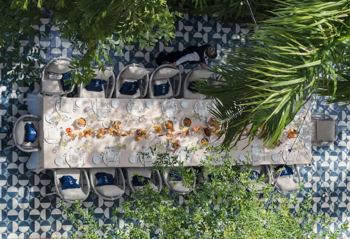 Overhead view of a long dining table set for guests at Il Giardino, surrounded by greenery. Mr. C Miami – Coconut Grove.