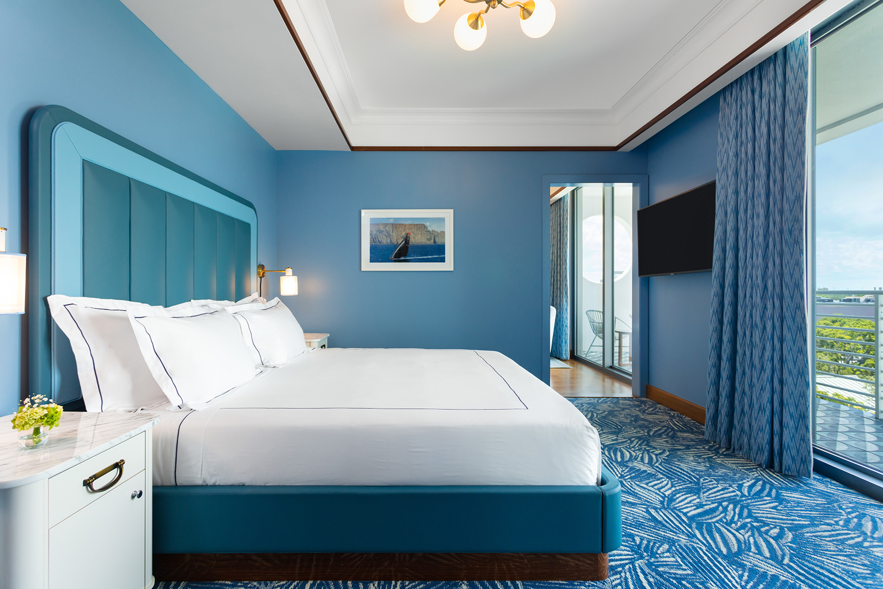 Vista do quarto king com cabeceira azul e carpete estampado. Mr. C Miami – Coconut Grove, um hotel de luxo em Miami.
