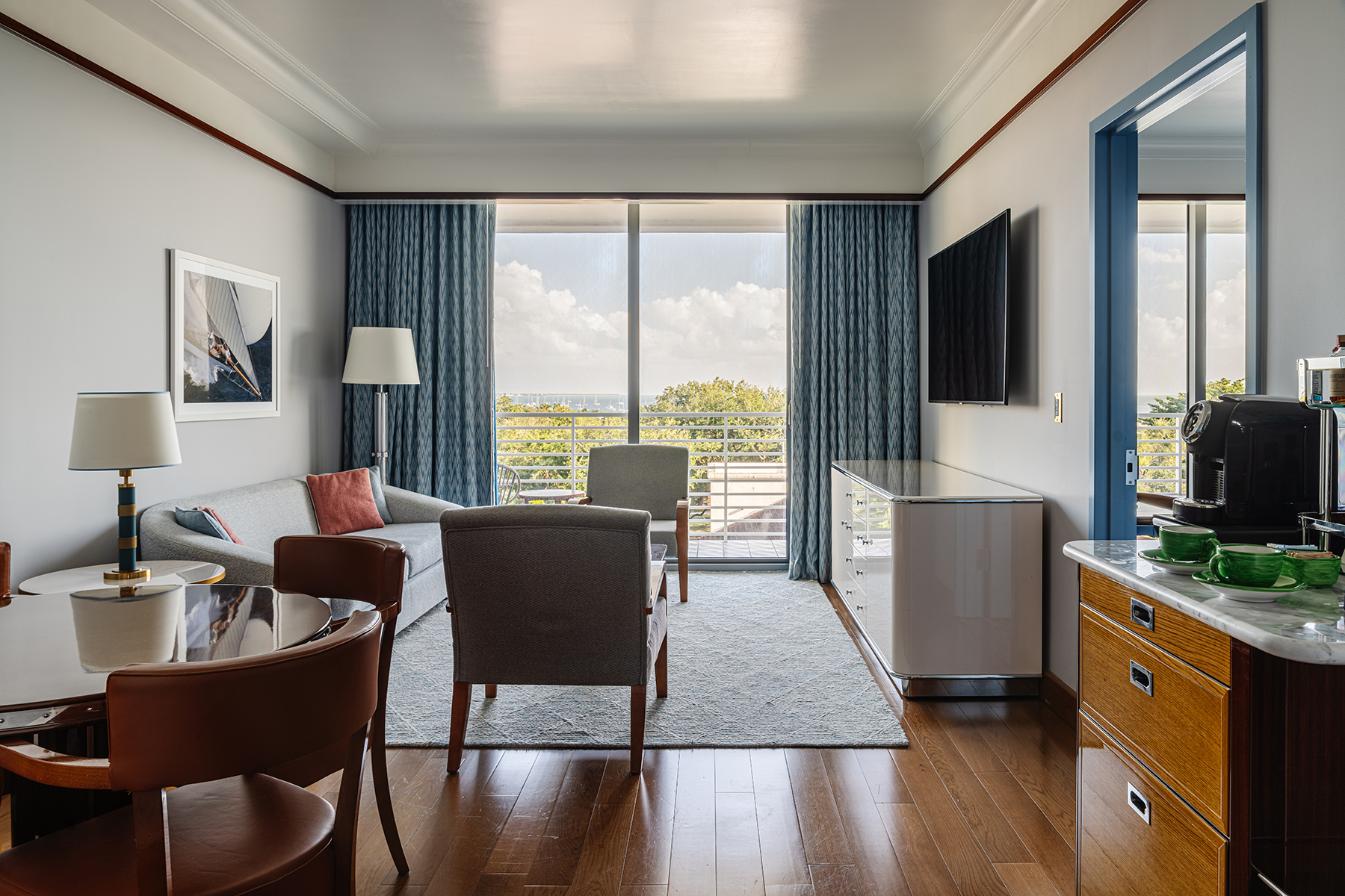 Área de estar com sofá cinza, poltronas e mesa de jantar. Mr. C Miami – Coconut Grove, um hotel de luxo em Miami.