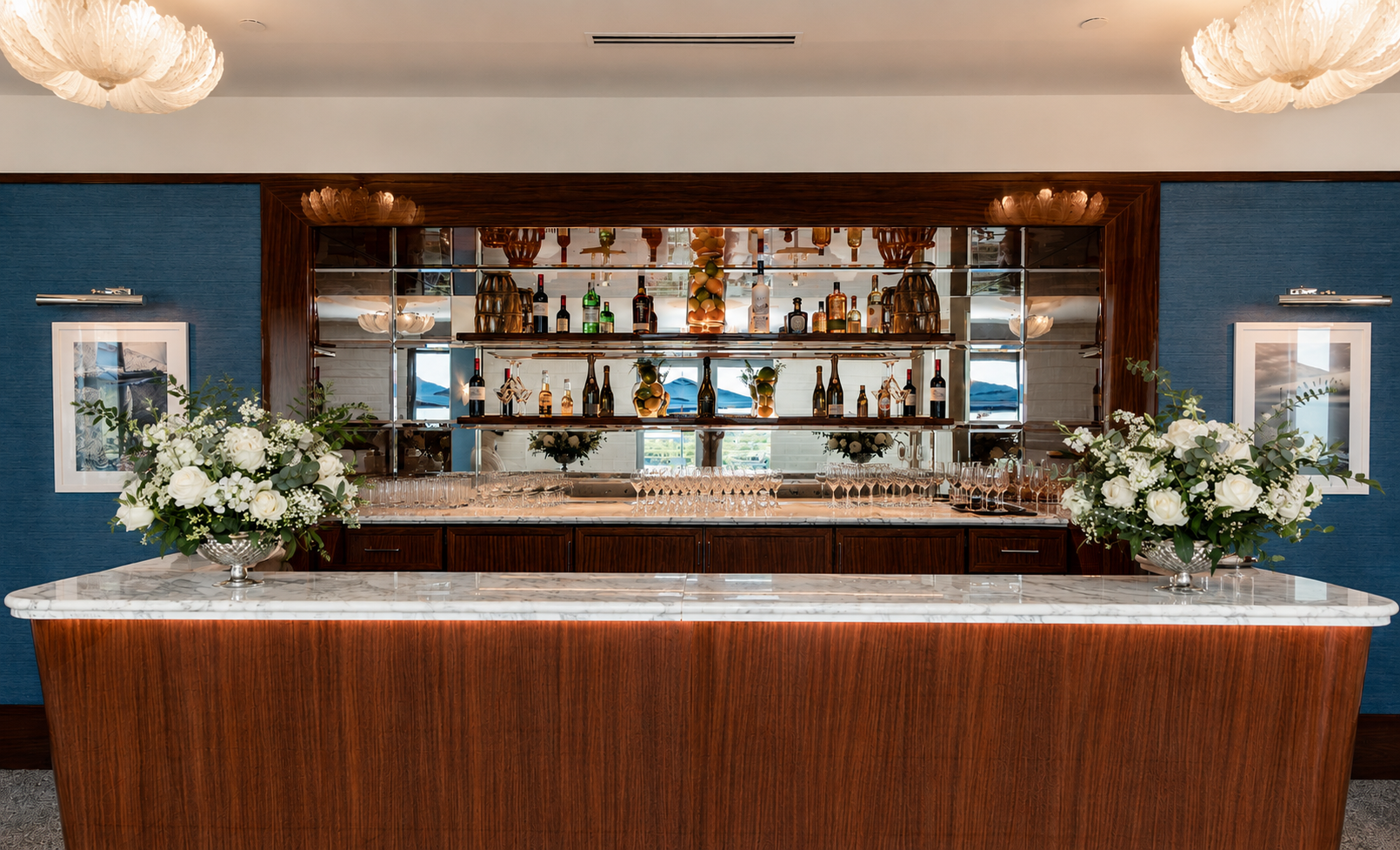 Bar counter at the Starlight Ballroom Foyer with mirrored shelving, liquor bottles, and stacked glassware. Mr. C Miami – Coconut Grove.