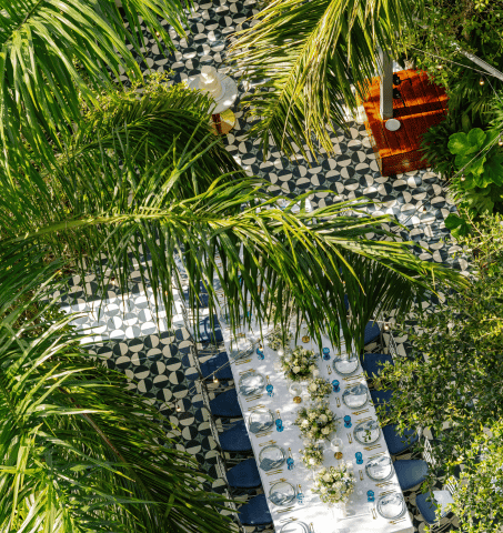 Tavolo da pranzo all'aperto immerso tra palme tropicali su un pavimento piastrellato al Mr. C Coconut Grove, hotel di lusso nel sud della Florida