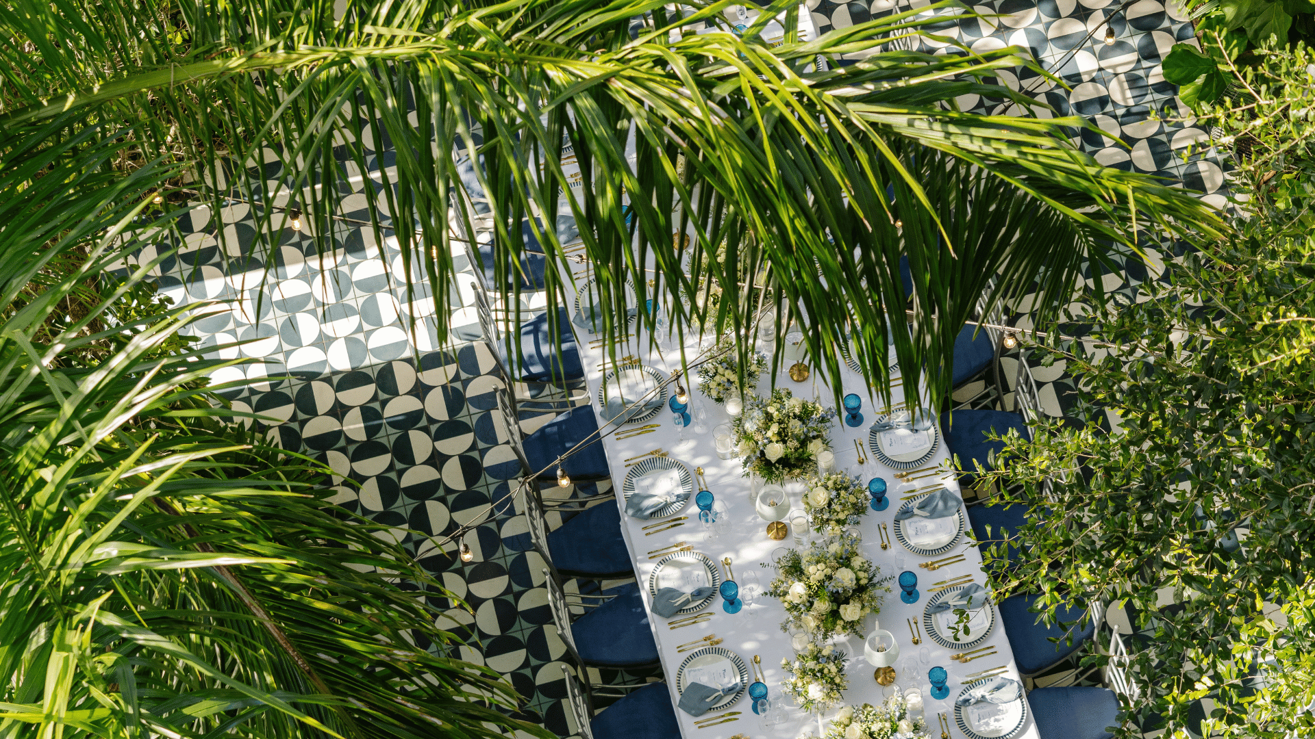 Tavola apparecchiata all'aperto con fiori bianchi in un rigoglioso cortile giardino al Mr. C Coconut Grove, hotel di lusso a Miami