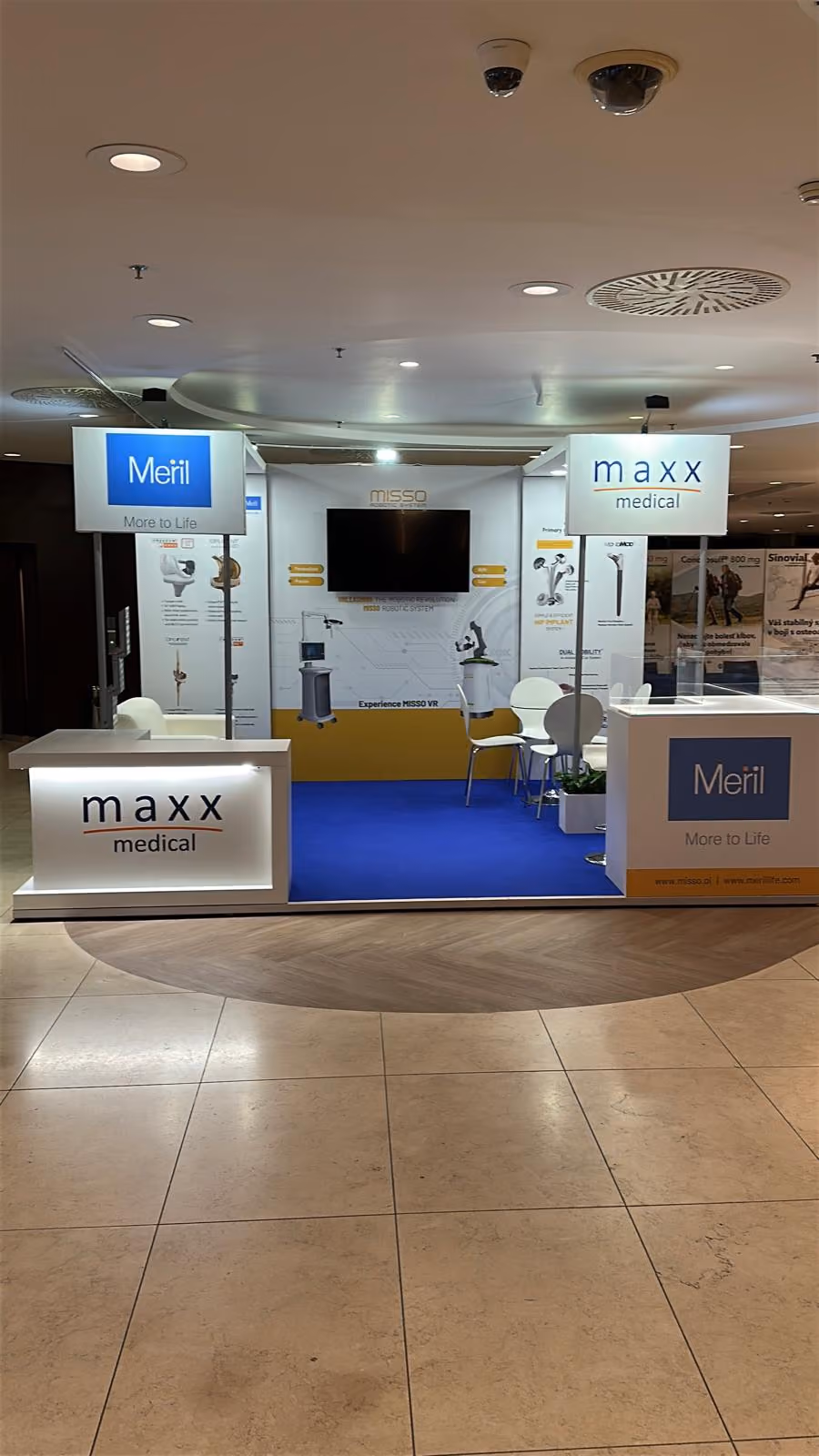 Maxx Medical exhibition stand with blue flooring, product displays, reception counters, and meeting area