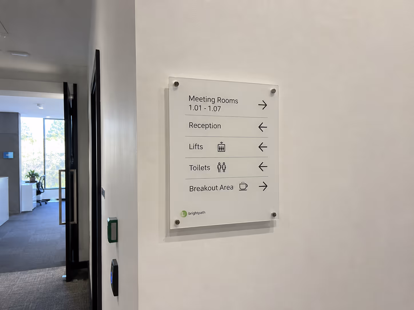 Office wall sign with directions to meeting rooms, reception, lifts, toilets, and breakout area.