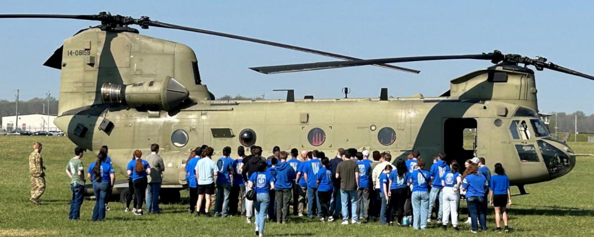 High school students examining a military helicopter up close during a Community Connections career exploration field trip