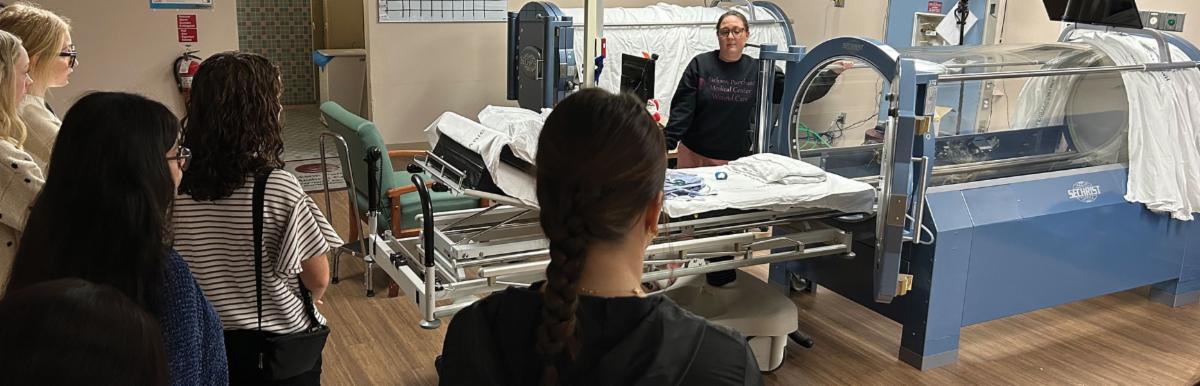 A Jackson Purchase Medical Center employee explaining medical imaging equipment to high school students during a Community Connections healthcare field trip