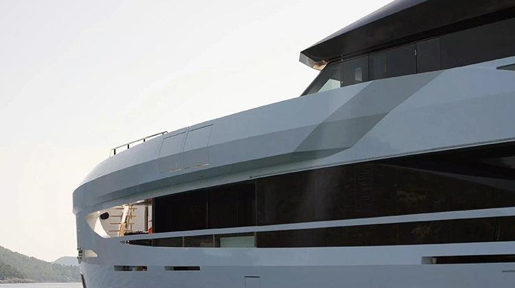 Close-up of the white side of a modern yacht with large dark tinted windows.