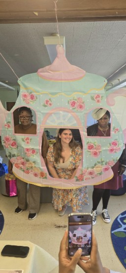 Three people posing behind a decorative Cinderella carriage photo prop