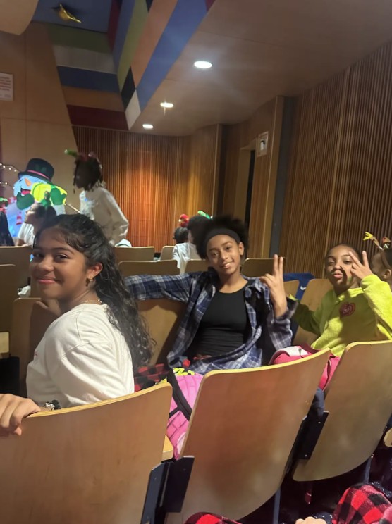 Students seated in auditorium smiling during a school assembly