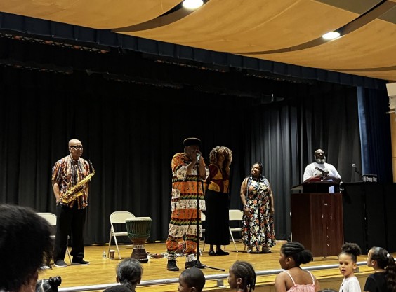 Performers in cultural attire present on school auditorium stage