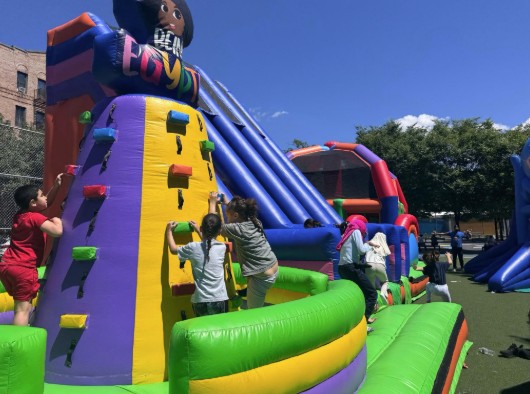 Students climbing inflatable rock wall at school outdoor celebration